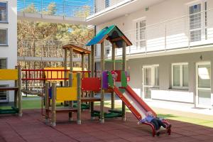a child laying on a slide at a playground at Niebieskie Apartamenty Rowy Apartament z klimatyzacją 100 m do plaży in Rowy