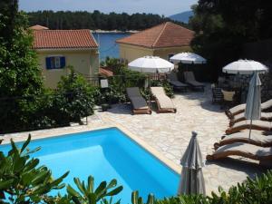 a swimming pool with chairs and umbrellas next to a house at Kiki Studios in Fiskardo