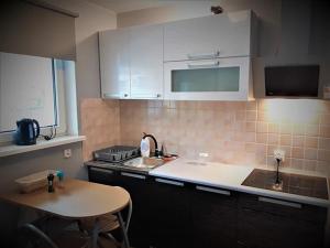 eine Küche mit weißen Schränken, einem Tisch und einem Waschbecken in der Unterkunft Apartament Wiktoria in Zakopane