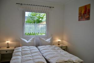 un letto con cuscini bianchi in una camera da letto con finestra di Ferienhaus Berlin a Blankenfelde-Mahlow