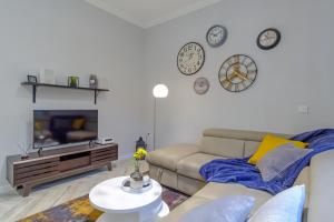 ein Wohnzimmer mit einem Sofa und Uhren an der Wand in der Unterkunft The Olive Green House in Burgas City