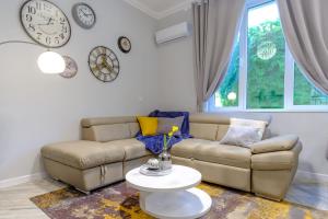a living room with a couch and clocks on the wall at The Olive Green House in Burgas City +40 photos