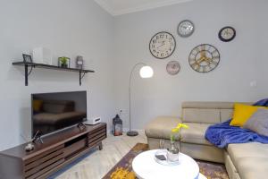 a living room with a couch and clocks on the wall at The Olive Green House in Burgas City