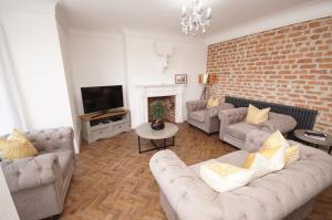 a living room with two couches and a brick wall at Grade 2 Listed Apartment, Southport Promenade in Southport