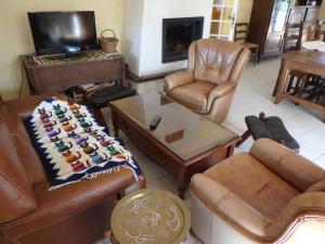a living room with leather furniture and a flat screen tv at LA CHENOPE in Souesmes