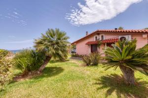 a house with palm trees in front of a yard at Villa Ergina in Agios Nikolaos
