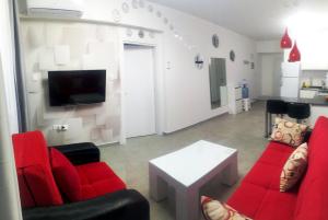 a living room with red chairs and a tv at Angel's Apartment at Caesar Resort in Trikomo