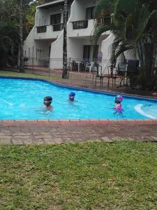 three people are swimming in a swimming pool at Unit 19 Villa Mia Apartment in St Lucia