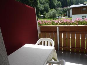 uma mesa branca e cadeira numa varanda com flores em Hörtmairhof em Campo Tures