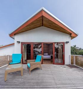 two chairs on a deck with a house at Kinan Retreat in Fulidhoo