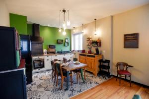 - une cuisine avec une table, des chaises et des murs verts dans l'établissement L'EN VERT, à Bagnères-de-Bigorre