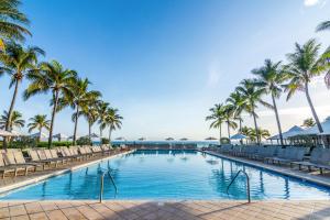 a swimming pool with palm trees and chairs at Hilton Rose Hall Resort & Spa in Montego Bay