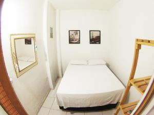 um pequeno quarto branco com uma cama e um espelho em Confortável Cobertura Copacabana no Rio de Janeiro