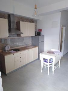 a kitchen with white cabinets and a table and a table and chairs at Apartment Iris in Drasnice