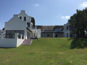 a large white house with a grass yard at Thatch House on the Canals in St Francis Bay