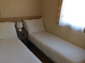 two beds in a small room with a window at 74, Orchard Park in Paignton