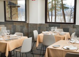 a dining room with tables and chairs and windows at Villa Lucerna Sports & Hotel Resort in Vigo de Sanabria