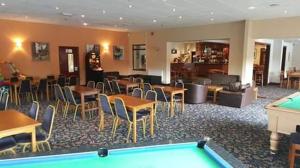 a hotel room with a pool table and tables and chairs at Glangwna Holiday Park in Caernarfon