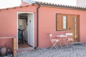 ein rosafarbenes Haus mit Stühlen und einem Tisch davor in der Unterkunft Alek in Novigrad Istria