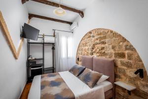 1 dormitorio con cama y pared de ladrillo en Casa De La Sera, en Rodas