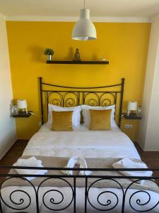 a bedroom with a large bed with a yellow wall at Al Casa Paquito in Almograve