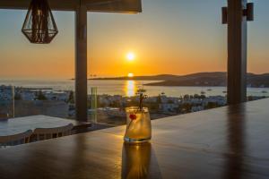 a table with a glass vase with a candle on it with the sunset at Sunset View Hotel in Parikia