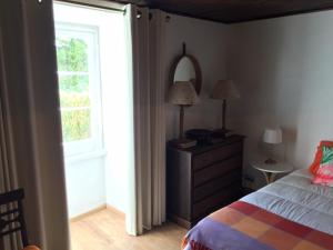 a bedroom with a bed with a dresser and a window at Quinta das Rosas in Capelas