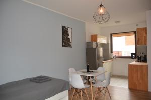 a bedroom with a bed and a kitchen with a table and chairs at Apartament Fibra Flat White in Rybnik