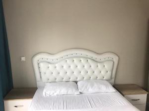 a white bed with a white headboard and two pillows at Medıkule(8) 1+1 in Istanbul