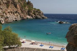 a beach with a group of people in the water at Roses Studios in Karpathos
