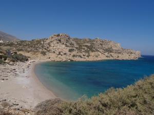 a beach with blue water and a mountain at Roses Studios in Karpathos
