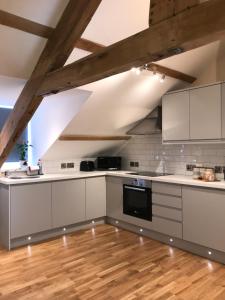 a kitchen with white cabinets and a wooden floor at Apartment 4, 1 Laura Place in Aberystwyth