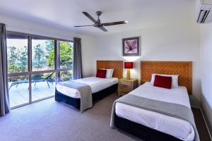 a hotel room with two beds and a balcony at Cooinda Gardens on Hamilton Island by HIHA in Hamilton Island