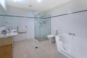 a bathroom with a shower and a tub and a toilet at Cooinda Gardens in Hamilton Island
