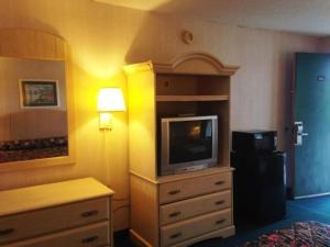 Habitación de hotel con TV en un tocador con cama en Royal Inn Columbia/Fort Jackson en Columbia