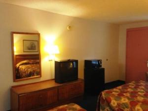 Habitación de hotel con TV y cama en Royal Inn Columbia/Fort Jackson en Columbia