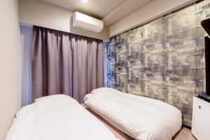 a hotel room with two beds and a painting on the wall at Grids Tokyo Asakusa-bashi Hotel＆Hostel in Tokyo