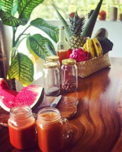 una mesa de madera con tarros de zumo y una cesta de fruta en Balangan Inn Surf Homestay, en Jimbaran