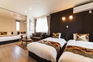 une chambre d'hôtel avec deux lits et un canapé dans l'établissement Ambicia Sasebo, à Sasebo