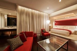 a hotel room with a red couch and a bed at Cross Hotel Sapporo in Sapporo