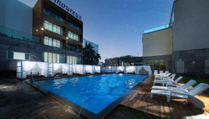 a large swimming pool with lounge chairs in front of a building at Amoureux Resort in Jeju