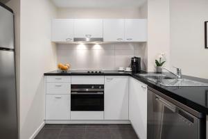 a kitchen with white cabinets and white appliances at Quest Narre Warren in Narre Warren