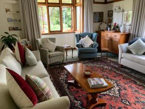 ein Wohnzimmer mit einem Sofa, Stühlen und einem Tisch in der Unterkunft Hawkes Bay Villa-Beechwood in Hastings