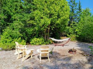 a group of chairs and a hammock in a yard at New Buddha Bing Unique Experience Cottage and Cabins in Tobermory