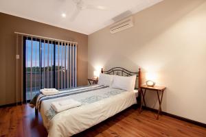 a bedroom with a large bed and a large window at Marina Views Townhouse in Darwin