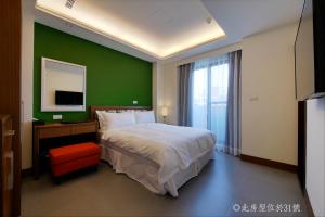 高雄的住宿－碧港良居商旅-西子灣 ，一间卧室设有一张大床和绿色的墙壁