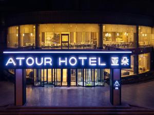 una señal de hotel frente a un edificio por la noche en Atour Jiaozhou Qingdao Hotel en Qingdao