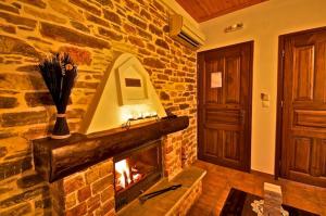 a living room with a fireplace in a stone wall at Archontiko Papoutsi in Mouresi