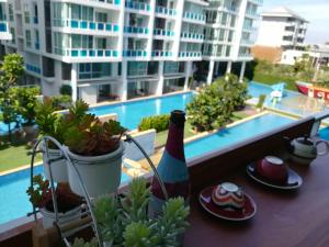 a bottle of wine and glasses on a balcony with a building at My Resort Hua Hin E306 in Hua Hin