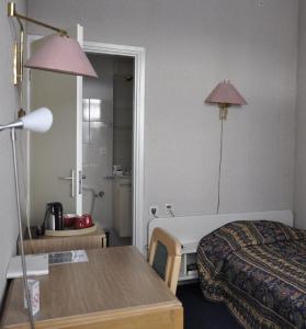 een hotelkamer met een bed, een tafel en een lamp bij Hotel Mayflower in Leiden